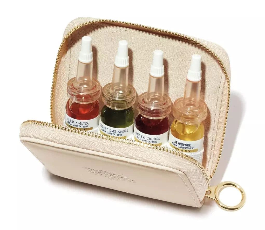 A beige BIOLOGIQUE RECHERCHE faux-leather zippered travel pouch for serums with a gold zipper and key ring, shown open with four 8ml serum bottles inside on a white background.